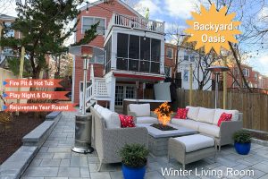 A backyard features a cozy outdoor living space with cushioned seating arranged around a fire pit. A red house with a screened porch is in the background. Text overlays read "Backyard Oasis," "Fire Pit & Hot Tub," "Play Night & Day," and "Rejuvenate Year Round.